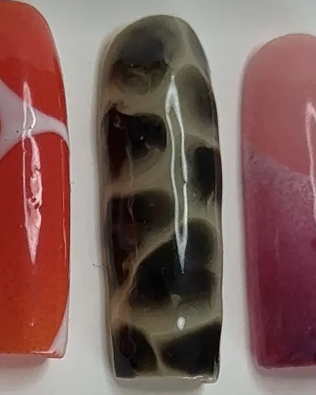 Ongle carré effet écaille de tortue : taches brunes et noires sur base ambrée.
