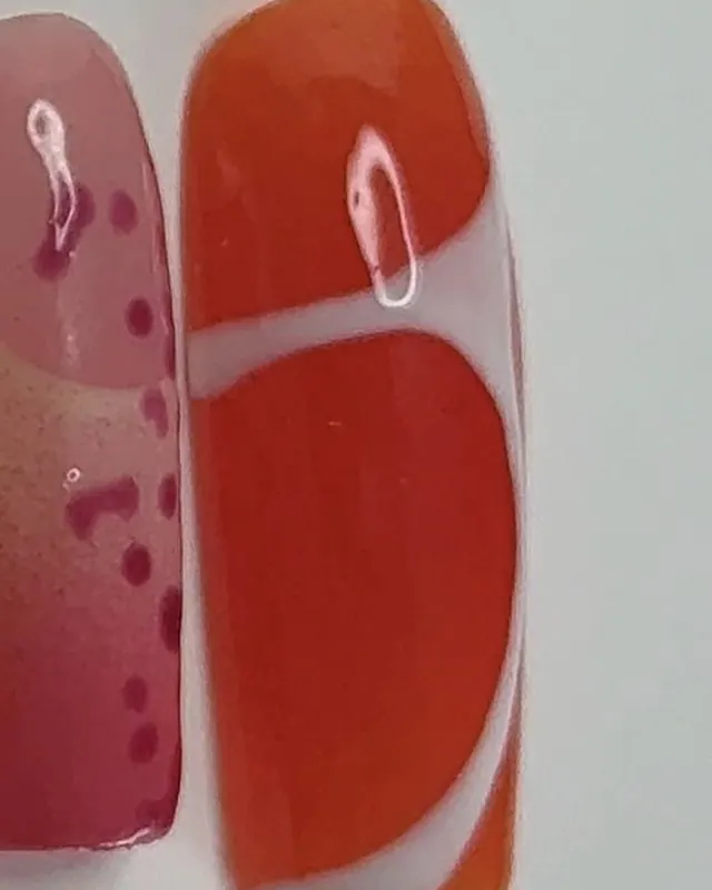 Ongle carré orange vif, traversé d’une courbe blanche.