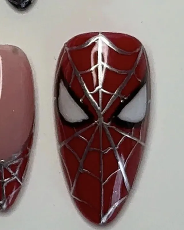 Le second masque de Spider-Man, à côté d’un ongle nude à french rouge.