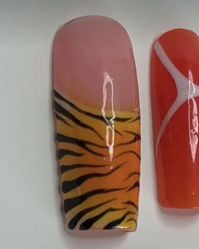 Ongle carré long : base rose, puis rayures de tigre noires sur un dégradé orange.